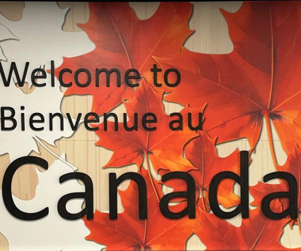 Welcome to Canada billboard with red and orange maple leaves